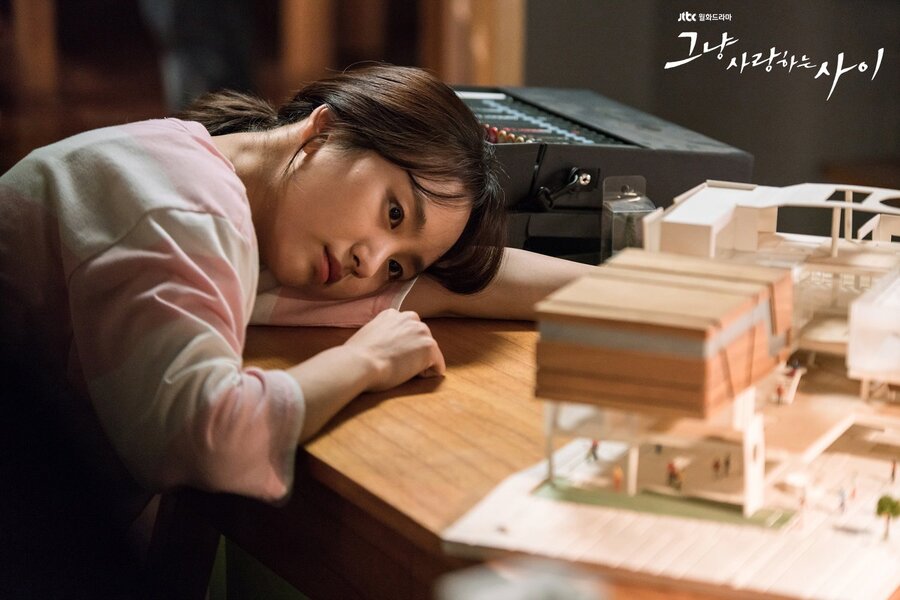 ha moon-soo dejectedly with her head down on a table, looking at a miniature model that she made