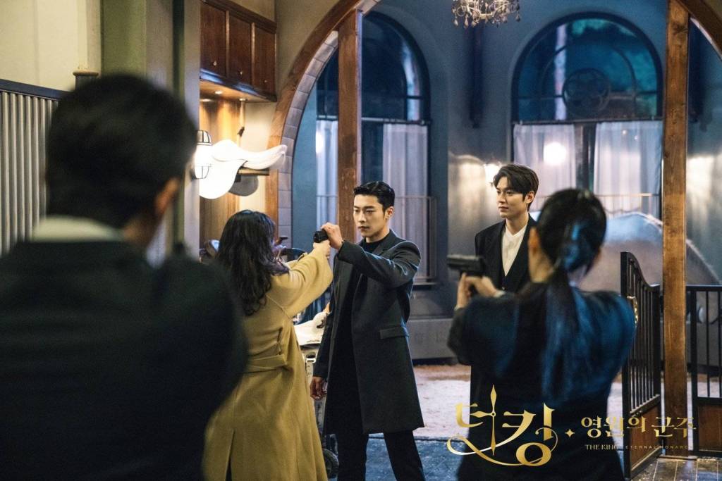scene from the king eternal monarch where jung tae eul points a gun at the king and the king's bodyguard stops her while two other guards point their guns at her